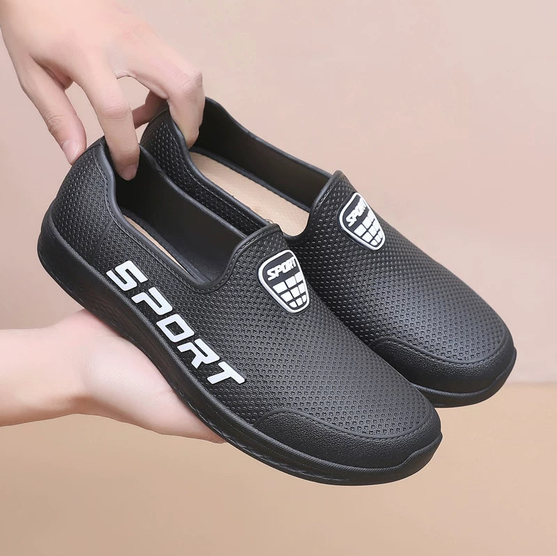 Mustat slip-on lenkkarit sport-logolla käsissä edestä — Helvenza