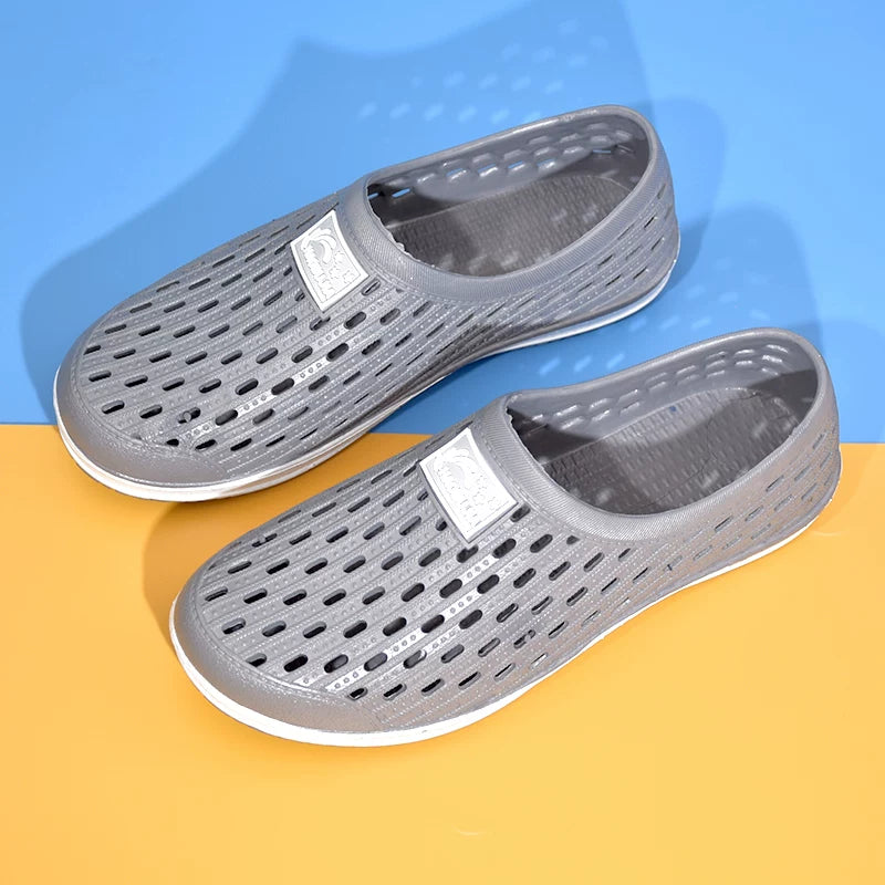 Harmaa reikäkuvioinen slip-on-tossu edestä valkoisella pohjalla — Helvenza