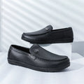 Mustat slip-on loaferit matalalla tummalla pohjalla sivulta — Helvenza