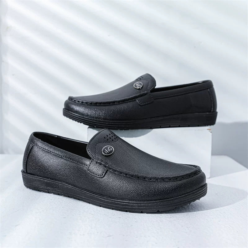 Mustat slip-on loaferit matalalla tummalla pohjalla sivulta — Helvenza