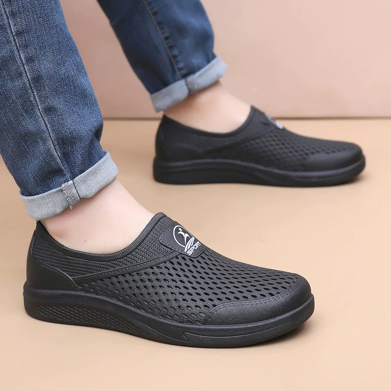 Mustat slip-on-tennarit lähikuva reikäkuviosta ja logodetaljista — Helvenza