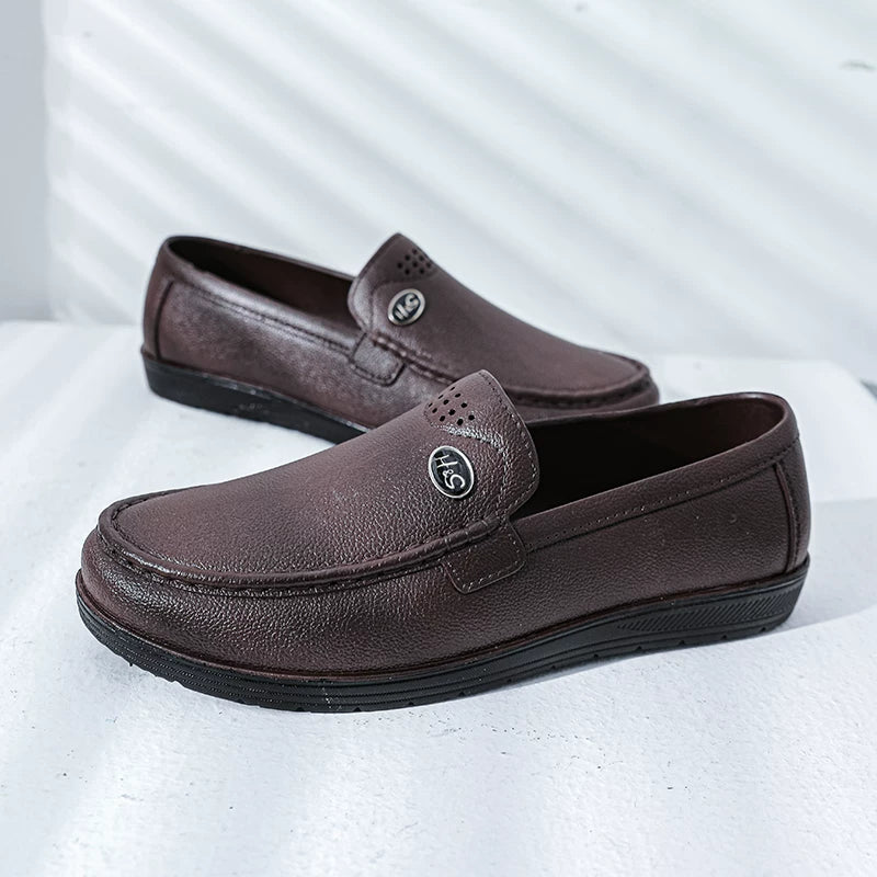 Tummanruskeat slip-on loaferit mustalla pohjalla sivulta — Helvenza