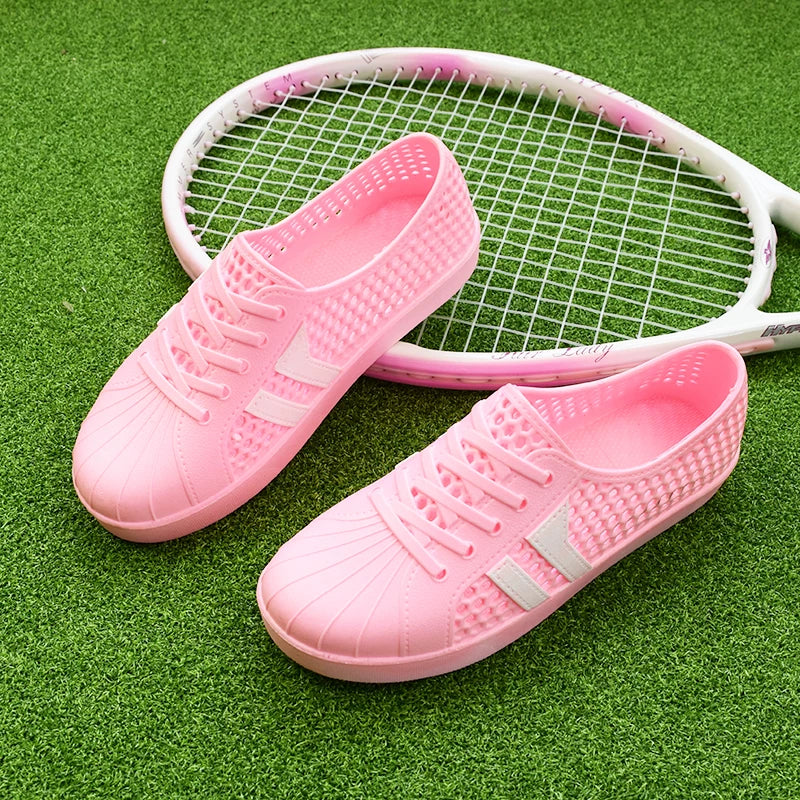 Vaaleanpunaiset rei'itetyt nauhalliset tenniskengät valkoisilla raidoilla sivulta — Helvenza