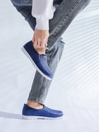 Siniset slip-on loaferit jalassa seisoma-asennossa valkoisella pohjalla — Helvenza
