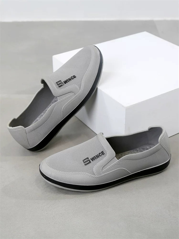 Harmaa slip-on tennari edestä ja sivulta mustalla kontrastipohjalla — Helvenza