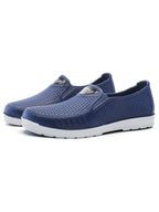 Siniset slip-on loaferit jalassa seisoma-asennossa valkoisella pohjalla — Helvenza