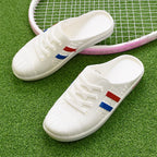 Valkoiset rei'itetyt mule-tenniskengät sivulta tennismaila taustalla — Helvenza