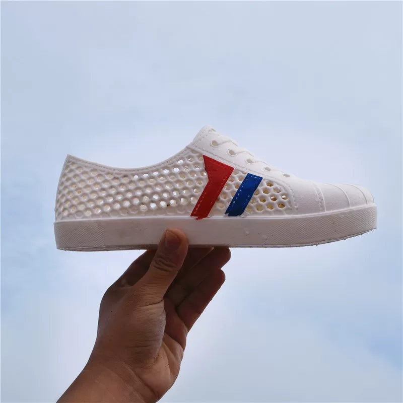 Valkoinen rei'itetty tenniskenkä sivulta käteen nostettuna lähikuva — Helvenza