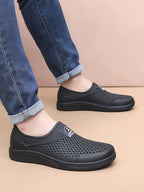 Mustat reikäkuvioiset slip-on-tennarit sivulta — Helvenza