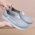 Harmaat slip-on lenkkarit sport-logolla käsissä edestä — Helvenza